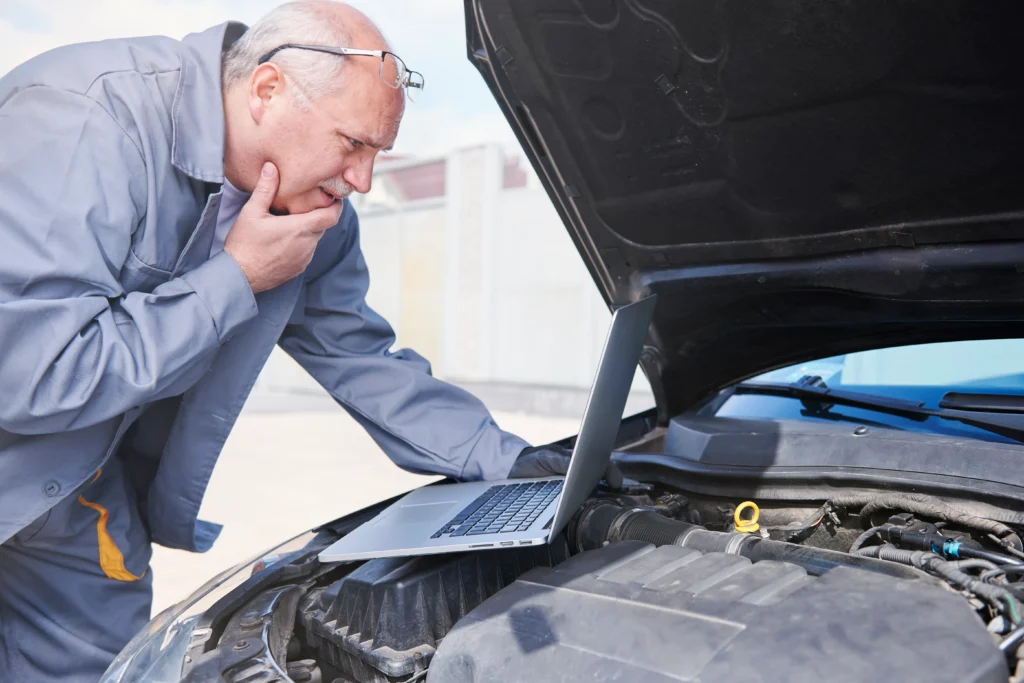 An elderly man trying to fix car battery replacement.